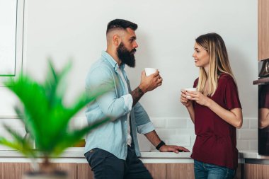 Genç ve güzel bir çift evdeki mutfakta kahve içerken...