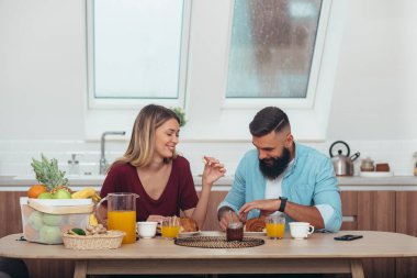 Genç ve çekici bir çift evdeki mutfakta kahvaltı yapıyor.