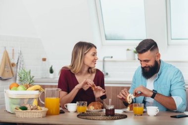 Romantik bir çiftin kahvaltıda kruvasan yediği bir fotoğraf.