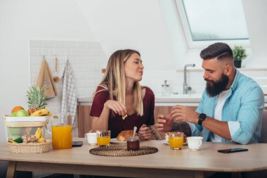 Evde ayçöreği yerken mutfakta kahvaltı eden bir çift.