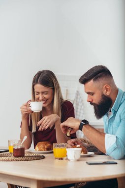 Mutlu bir çiftin kahve içip sohbet ederken kahvaltı etmesi.