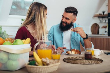 Aşık genç bir çiftin evdeki mutfakta kahvaltı etmesi.