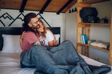 Pijamalı bir çift, rahat bir yatakta sarılıp sarılıyorlar. Evde romantik sabahlar. Yatak odasında birlikte olmanın ve rahatlamanın tadını çıkarıyorum. İlişki kavramı.