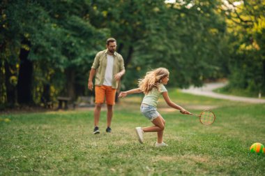 Genç bir kız elinde raketle çayırda eğlenceli bir badminton oyunu oynuyor. Sportif bir kız elinde raketle koşuyor ve etkileşimli bir spor oyunu oynuyor. Boşluğu kopyala,