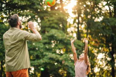 Güneşli bir yaz gününde doğada voleybol oynayan aktif bir baba ve kız. Aile spor gününü boş zamanlarında doğada geçirir. Dışarıda voleybol oynayan sportif bir aile. Boşluğu kopyala