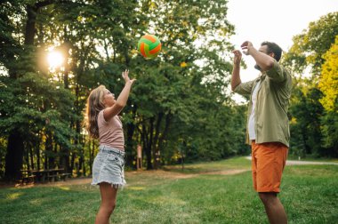 Aktif bir aile spor gününü doğada geçiriyor. Sportif bir baba ve kızı, güneşli bir yaz günü, ormanın yakınındaki bir çayırda voleybol oynuyorlar. Aile voleybol oynuyor.