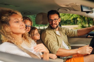 Yeni bir araba süren ya da şehirde test sürüşü yapan mutlu beyaz bir aile. Ebeveynler ve kızları tatili otomobille seyahat ederek ve yolculuğun tadını çıkararak geçiriyorlar. Bir babaya odaklan. Boşluğu kopyala.