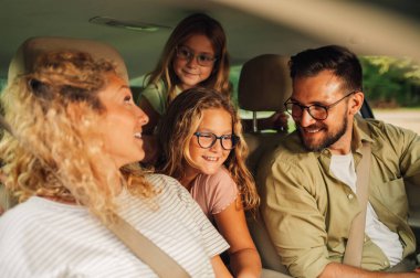 Dört kişilik mutlu bir ailenin portresi, hafta sonu şehir dışına giderken araba kullanmaktır. Ebeveynler yeni arabalarıyla kızlarıyla bir yolculuğa çıkıyorlar. Gözlüklü bir kıza odaklan..