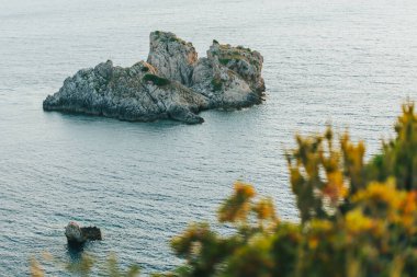 Öğleden sonra deniz kıyısında kayalık bir adanın çekimi