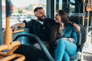 Genç ve güzel bir çift otobüste oturmuş sohbet ediyor, flört ediyor ve sarılıyorlar.