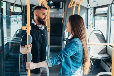 Birbirine aşık genç bir çift otobüste dikilirken birbirlerine bakıyorlar.