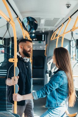 Hareket halindeki bir otobüste genç bir çift konuşurken ve flört ederken