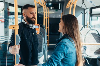 Hareket halindeki bir otobüste duran genç çift, konuşurken ve flört ederken...