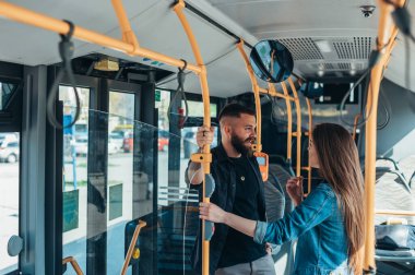 Hareket halindeki bir otobüste durmuş flört eden genç ve çekici bir çift.
