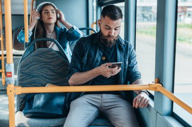 Genç ve güzel yolcular şehirde gün boyunca otobüsteyken akıllı telefon kullanıyorlar.
