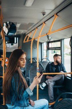 Genç ve güzel yolcular şehirde gün boyunca otobüsteyken akıllı telefon kullanıyorlar.