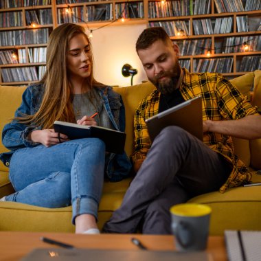 Birkaç öğrenci evde otururken dijital tablet ve kitap kullanıyor.