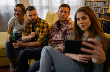 Ev partisinde eğlenirken toplu selfie çeken mutlu bir grup genç.