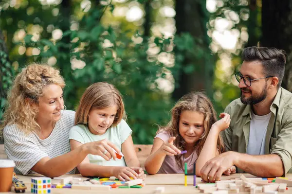 Dört kişilik mutlu bir aile doğada piknik masasında oturup eğlenceli bir masa oyunu oynuyor. Oyuncu aile, eğlenceli ahşap oyunlarla ve birlikte vakit geçirirken kuleler inşa etmekle rekabet ediyor..