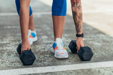 Dambıl kullanırken dışarıda antrenman yapan çekici bir kadın.