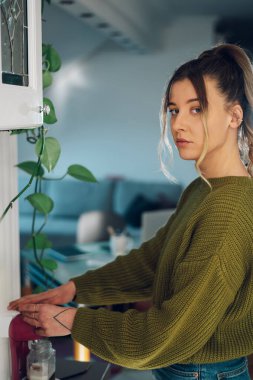 Genç ve güzel bir kadın evdeki bir mutfakta makinede taze espresso yapıyor. Barista kahve makinesi evde. Kahve makinesi kahve yapıyor..