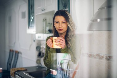 Genç ve mutlu bir kadın sabahları mutfakta kahve içiyor. Çekici bayan evde çay içmekten zevk alıyor.