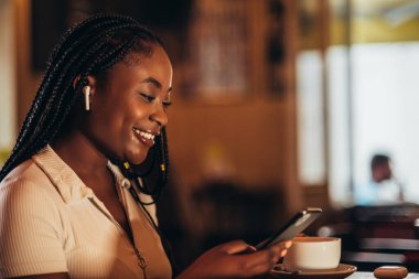 Güzel Afrikalı Amerikalı kadın kafedeyken akıllı telefon ve uçak kullanıyor.