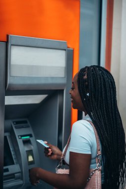 Çekici Afrikalı Amerikalı kadın kredi kartı kullanıyor ve ATM 'den para çekiyor.