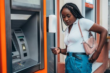 Güzel Afrikalı Amerikalı kadın ATM ve kredi kartı kullanıyor.