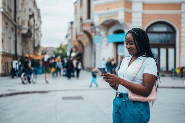 Güzel Afrikalı Amerikalı kadın şehir dışındayken akıllı telefon kullanıyor.