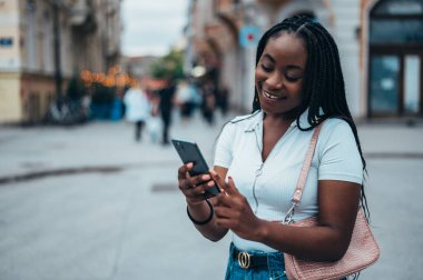 Güzel afro-amerikan kadın şehir dışındayken akıllı telefon kullanıyor.