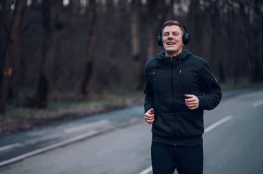 Genç kızıl saçlı adam dağ yolunda koşarken uzun mesafe kardiyo antrenmanı yapıyor. Spor konsepti, sağlıklı yaşam tarzı, motivasyon.