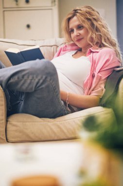 Kafkasyalı hamile bir kadının portresi rahat bir sandalyede oturup evde vakit geçirirken bebek gelişimiyle ilgili kitap okuyor. Hamilelik hayatı doğuma hazırlanma ve çocuk yetiştirme.