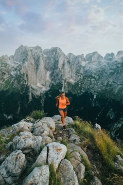 Vahşi doğada kayalık dağlarda koşan ve yol boyunca koşan bir kadın gökdelen. Vahşi doğada dağcılık yaparken koşan, koşan ve iz süren aşırı sporcu bir kadın. Bir skyrnner yükseklikle çalışır.