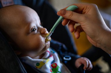 Annem onu beslerken bebek maması yiyen sevimli bir bebek.