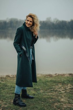 Nehrin kenarında yeşil ceketli genç sarışın kadın.