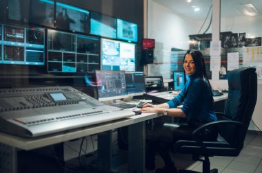 Televizyon istasyonunda yayın kontrol odasında yapımcı olarak çalışan orta yaşlı güzel bir kadın. Prodüksiyon yapımcısı. Televizyon..