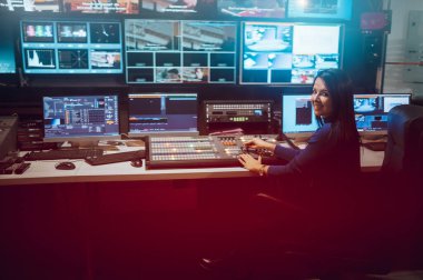 Televizyon istasyonunda yayın kontrol odasında yapımcı olarak çalışan orta yaşlı güzel bir kadın. Prodüksiyon yapımcısı. Televizyon..
