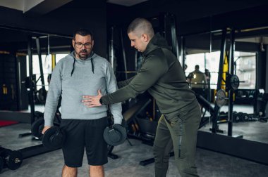 Spor salonunda spor salonunda spor yaparken halterleri kullanan orta yaşlı adamlar. Şişman adam kilo vermeye çalışıyor..