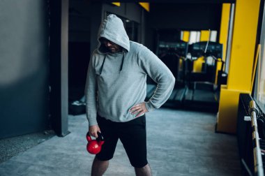 Spor salonunda egzersiz yaparken kettlebell kullanan orta yaşlı şişman adamlar. Kilo vermeye çalışan şişman bir adam. Obez adam spor yapıyor..