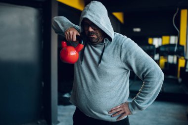 Kilolu orta yaşlı adamlar spor salonunda kettlebell kullanırken antrenman yapıyorlar. Kilo vermeye çalışan şişman bir adam. Isınıyorum..