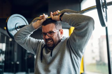 Spor salonundaki şişman, orta yaşlı adam halter kaldırma egzersizleri yapıyor. Sağlıklı yaşam tarzı kavramı. Fazla kilolu.