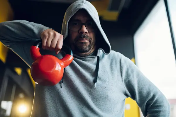 Spor salonunda egzersiz yaparken kettlebell kullanan orta yaşlı şişman adamlar. Kilo vermeye çalışan şişman bir adam. Obez adam spor yapıyor..