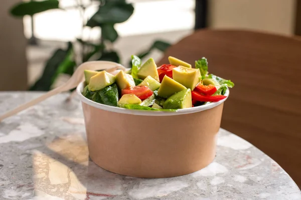 stock image Avocado and fresh tomatoes salad in bowl on gray stone background top view. Concept Food For Parties. Fast Food. Healthy lunch. Food delivery in disposable plate of craft paper. Eco-friendly carton