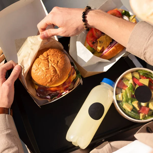 stock image American fast food specialties. lunch on a tray, burger with meat, hot dog. Fast food on the street, top view