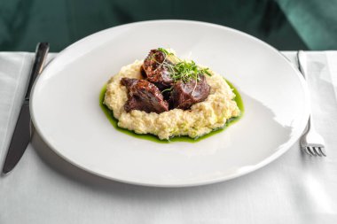 Stewed Veal cheeks with hominy on plate, copy space. food concept.