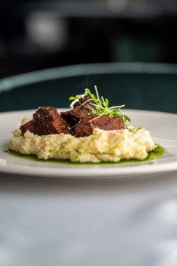 Stewed Veal cheeks with hominy on plate, copy space. food concept.