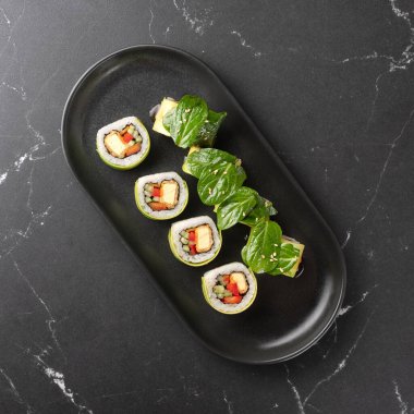 Siyah tabakta tofu ve sebzeli vejetaryen suşi. Vegan gıda konsepti. sağlıklı renkli yiyecekler