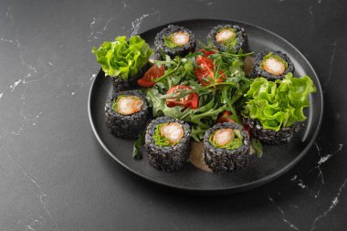 Siyah pirinç, avokado ve siyah tabakta tatlı patatesli vejetaryen suşisi. Vejetaryen gıda konsepti.