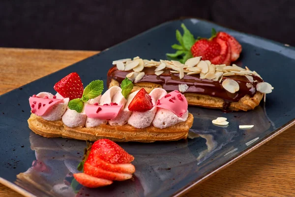 Set of french dessert eclairs. Traditional french eclairs with chocolate and strawberries, serving in a restaurant, menu food concept.